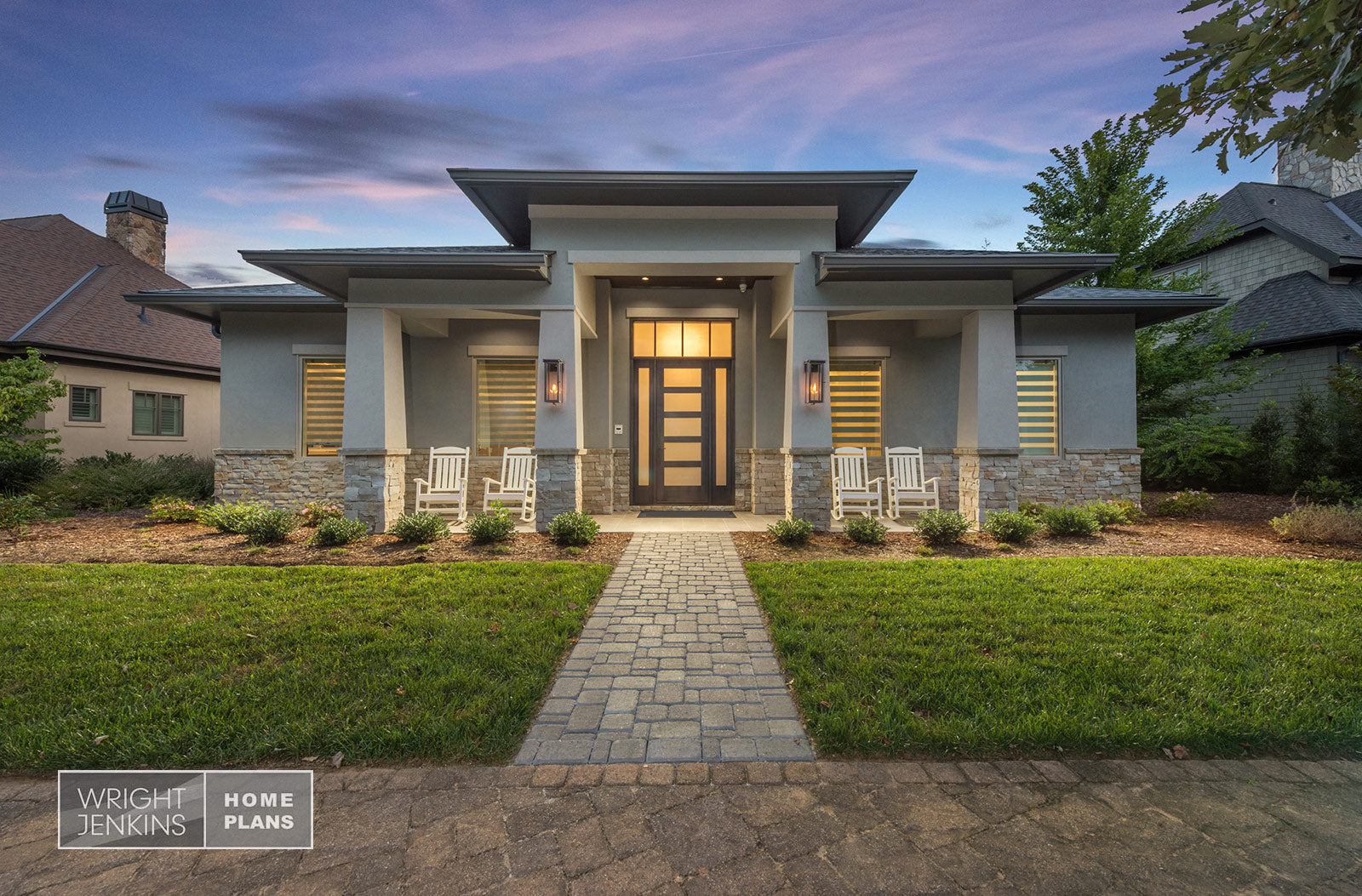 Front exterior view of a modern single-story home with stacked stone water table. Glass front door with side lights and transom window above.