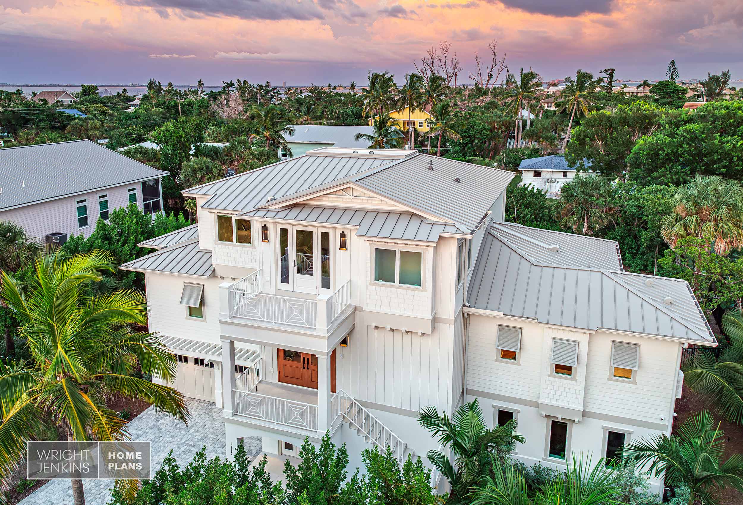 Three-story coastal cottage with metal roof and open decks front to back. Shuttered windows and pergola for shade.